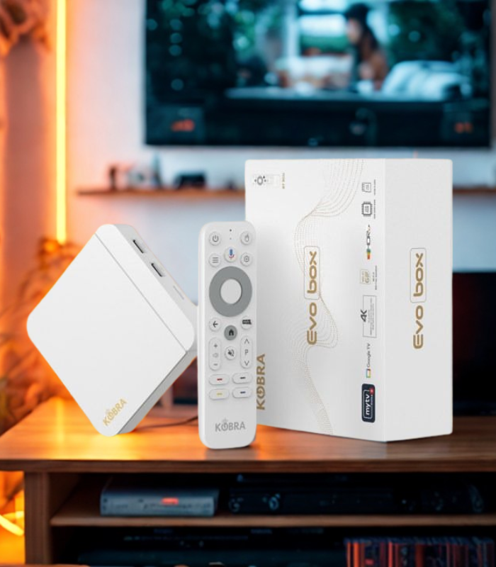 Kobra Evo Box with remote control and packaging on a wooden surface with a TV in the background.